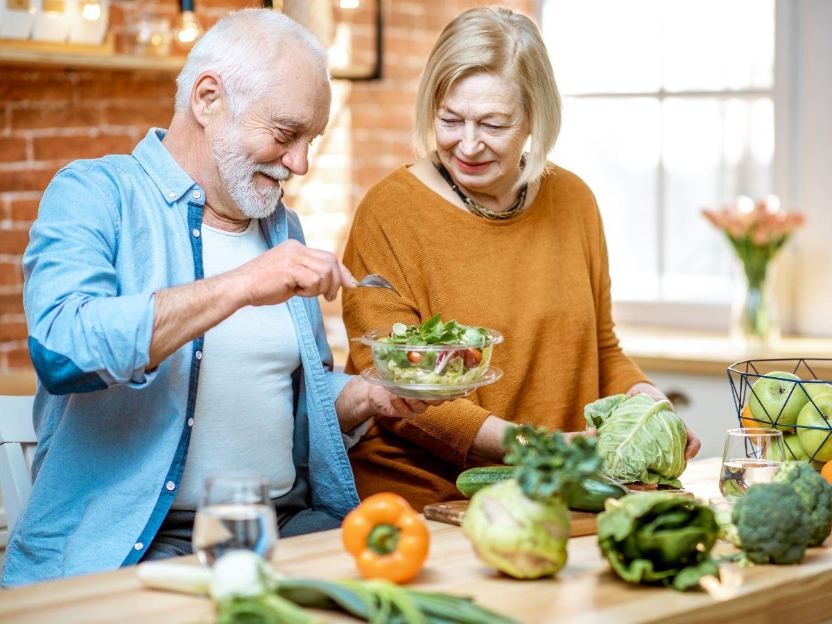 Image where Old man cutting vegetables in the kitchen with his wife for a healthy recipe